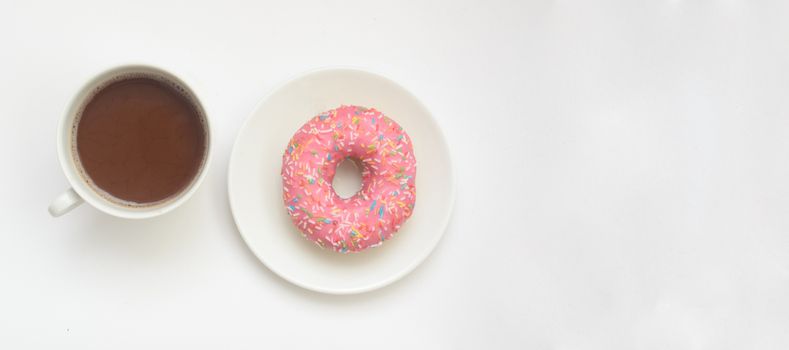 A cup of cacao drink and pink donut on white background, space for text.