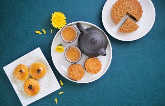 Moon cake for Mid-Autumn Festival, delicious beautiful fresh mooncake on a plate over blue background table, top view, flat lay layout design concept.