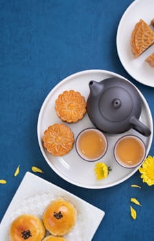 Moon cake for Mid-Autumn Festival, delicious beautiful fresh mooncake on a plate over blue background table, top view, flat lay layout design concept.