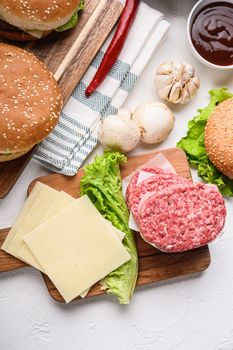 Set of burger raw ingredients and ground beef on white textured background, topview.