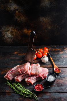 Fresh raw pork meat from organic farm with spices: pepper, salt, bay leaf. Butcher chopping cleaver in wood table over rustic wood and metal Food background top side view .