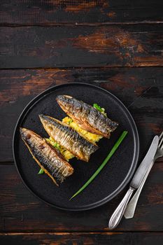 Roasted mackerel fish with garlic, paprika and saffronon dark wooden table, top view with copy space.
