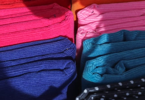 Detailed close up view on samples of cloth and fabrics in different colors found at a fabrics market.