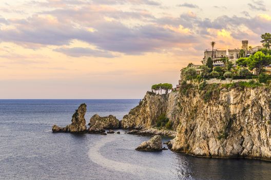 Sunset landscape on the sicilian coast farallones at the height of the town of tahormina italy