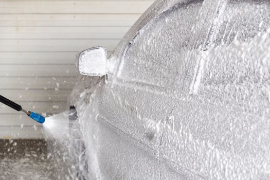 A process of applying soap sud in indoor carwash station - closeup with selective focus and background blur.