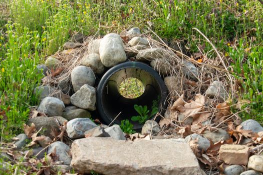 Looking Through a French Drain With a Black Pipe and Large Rocks Surrounding It