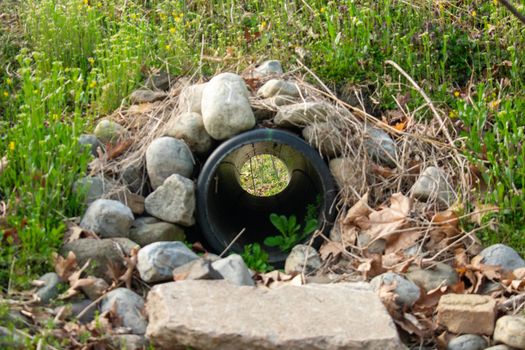 Looking Through a French Drain With a Black Pipe and Large Rocks Surrounding It