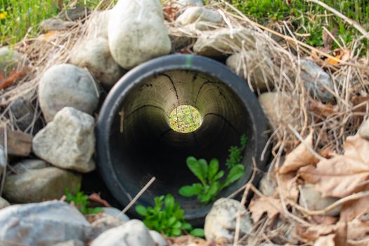 Looking Through a French Drain With a Black Pipe and Large Rocks Surrounding It