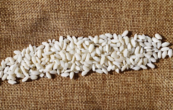 White uncooked rice on brown cloth ,regular long grains