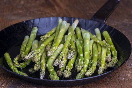 fresh green asparagus in a pan on dark wood