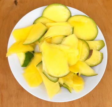 Pineapple sliced in a plate, on a wooden background.