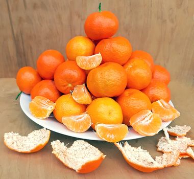 A plate full of clementines, on a wooden background