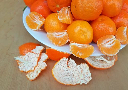 A plate full of clementines on a wooden background