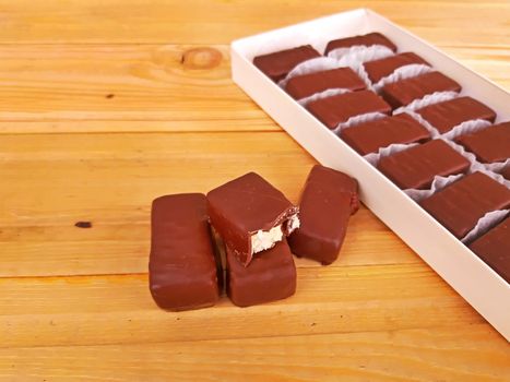 Assorted sweet chocolates in a box on wooden background.