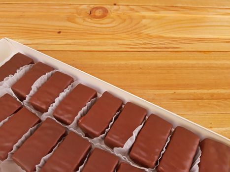 Delicious sweet chocolates in a box on wooden background.