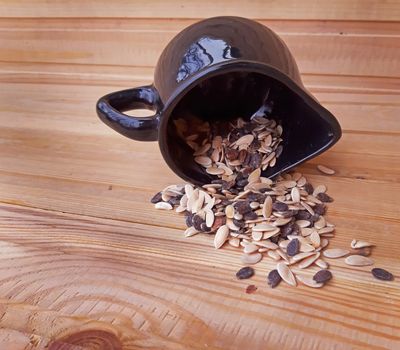 Bowl with seeds overturned on wooden background.