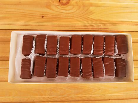 Delicious sweet chocolates in a box on wooden background.