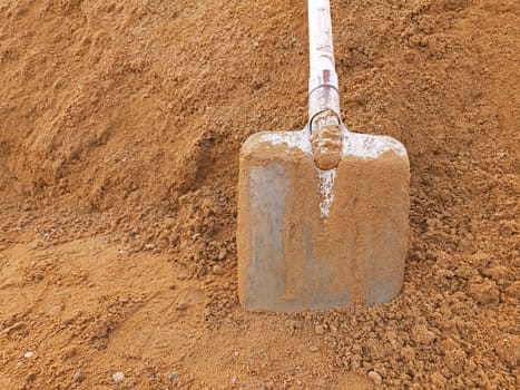 A shovel in construction sand with copy space.