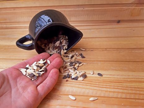 Bowl with seeds overturned on wooden background.