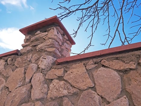 Thick stone fence on blue sky background.