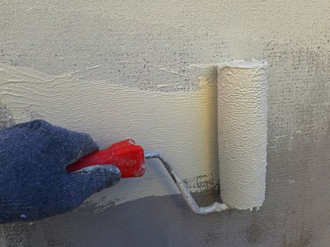 Wall painting with a roller. White-yellow paint.