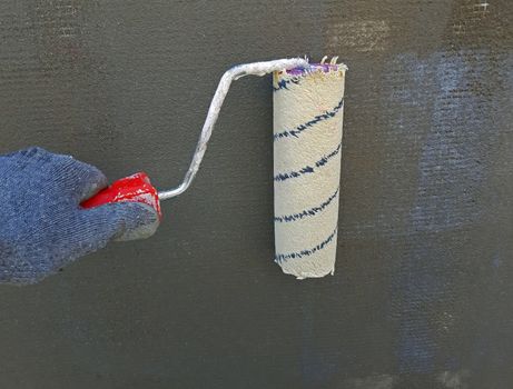 Wall painting with primer paint with a large brush.
