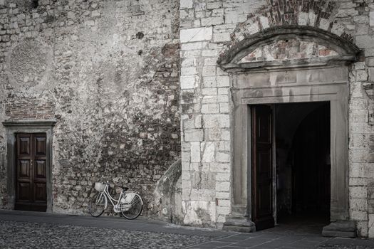 Bicycle leaning against the brick wall of a church with the door open, street photography