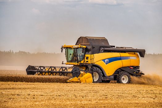 Modern Combine Harvester With a Large Mower in a Wheat Field. Agricultural Seasonal Work.