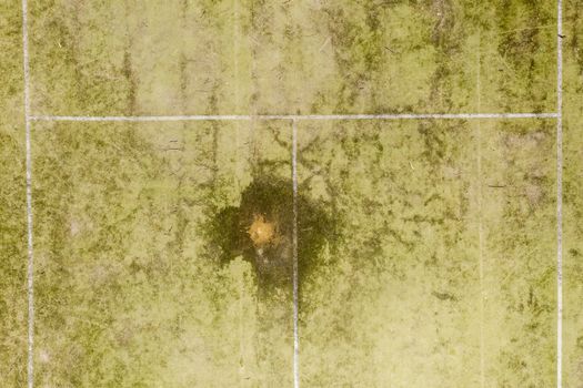 An aerial view of an old unused tennis court in disrepair in a public park in a small regional township