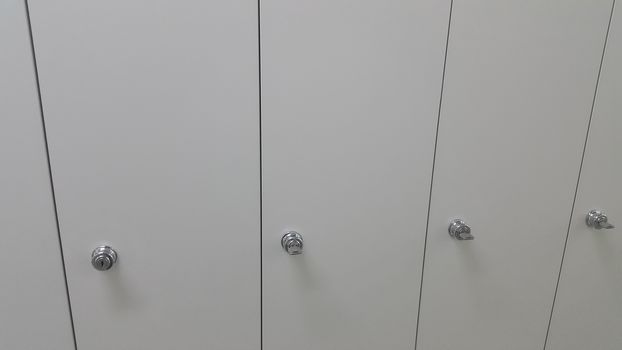 Perspective view of lockers or cupboards in a row with white doors, keys and locks
