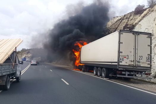 Burning truck on the road. The cab of the truck is on fire.