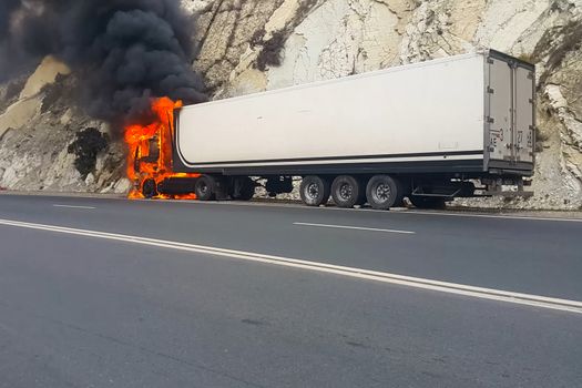 Burning truck on the road. The cab of the truck is on fire.