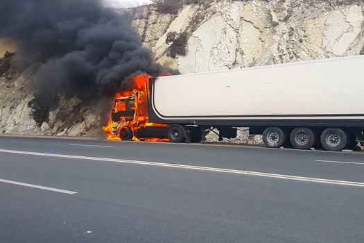 Burning truck on the road. The cab of the truck is on fire.