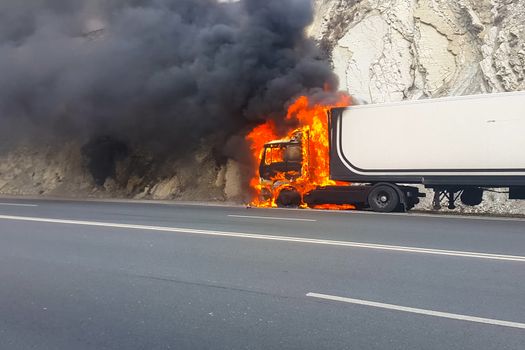 Burning truck on the road. The cab of the truck is on fire.