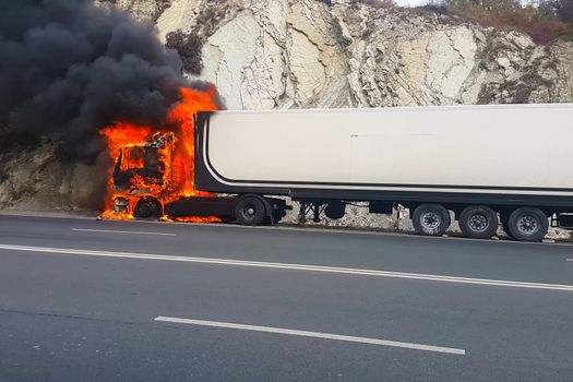Burning truck on the road. The cab of the truck is on fire.