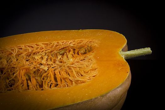 Cut ripe orange pumpkin on black background