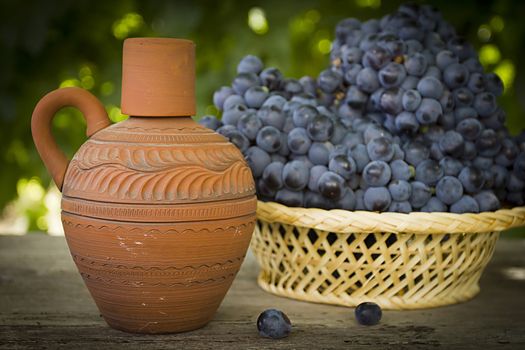 Clay jug with wine and grapes outdoors