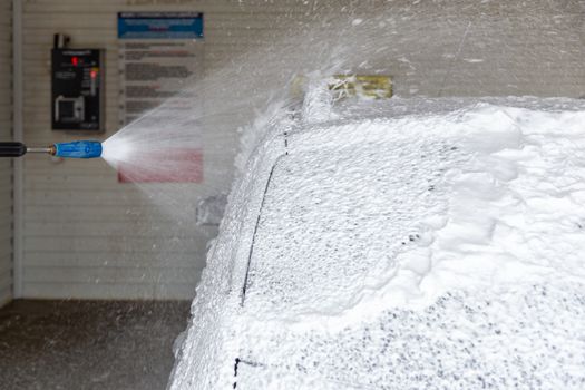 A process of applying soap sud in indoor carwash station - closeup with selective focus and background blur.