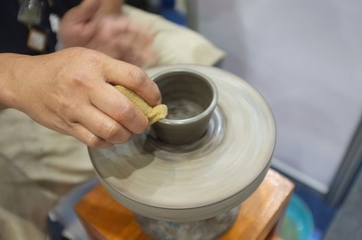 Concept Ceramic workshop. The man Throwing clay bowl on a pottery's wheel.