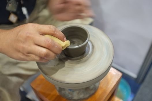 Concept Ceramic workshop. The man Throwing clay bowl on a pottery's wheel.