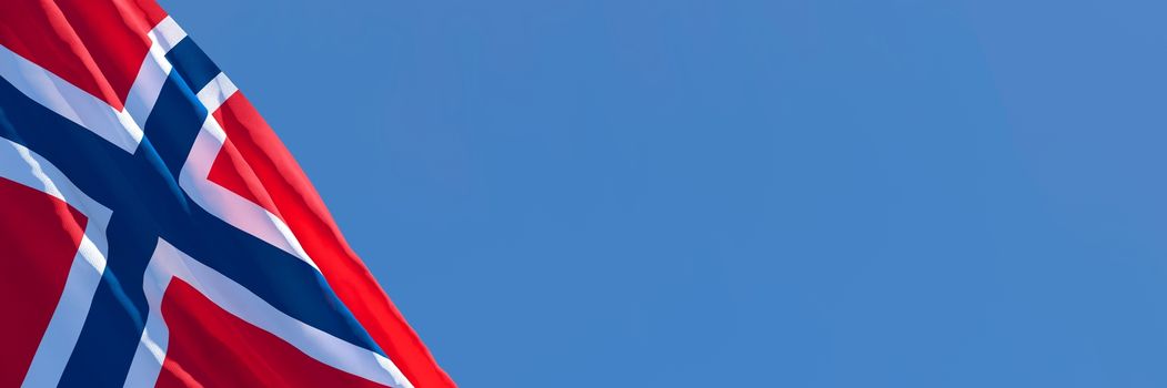 3D rendering of the national flag of Norway waving in the wind against a blue sky