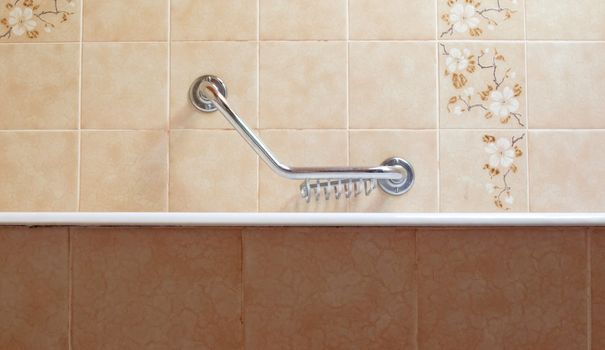 Old bathroom, brown tiled interior with bathtub, assistive handle