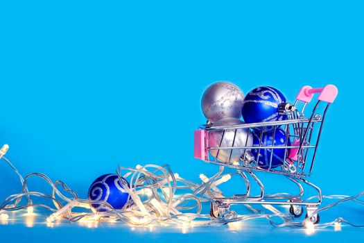 Christmas balls and Christmas garlands lie in a shopping cart. Purchase of holiday accessories