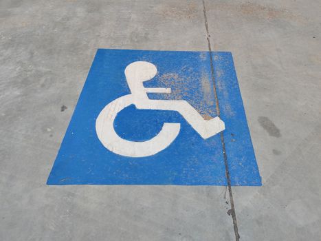 Blue sign on the asphalt about disabled parking