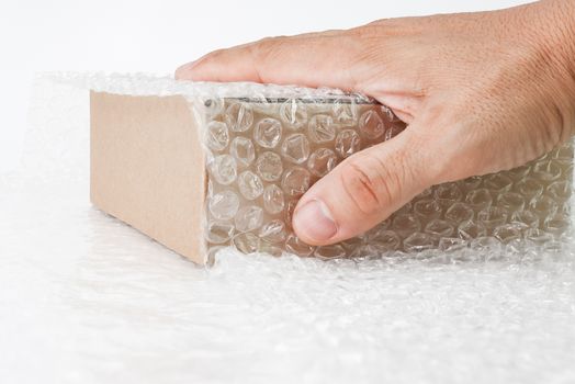 hand of man hold Bubbles covering the box by bubble wrap for protection product cracked  or insurance During transit -isolated white background 
