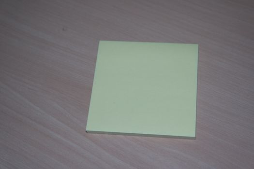 Close-up, selective focus: Yellow sticky note paper placed on a wooden table with copy space for text