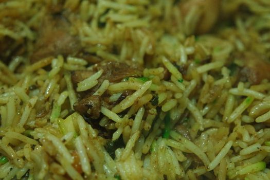 A close up view with selective focus of cooked white Basmati rice pulao or biryani with chicken meat