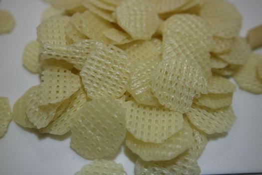 Closeup view with selective focus on dried chips as fast food for tea break. Potato chips with spices sprinkled on it. Fast food background for advertisements.