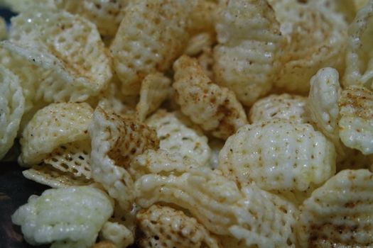 Closeup view of freshly fried chips as fast food for tea break. Potato chips with spices sprinkled on it. Fast food background for advertisements.