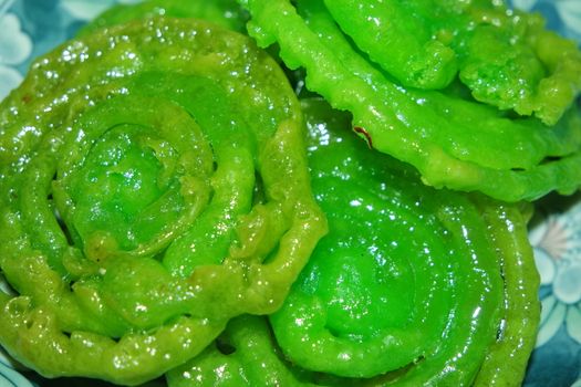 Crispy sweet Asian dessert green Jalebi cooked and served in Festival, Indian sweet street food with juicy syrup, a closeup view.